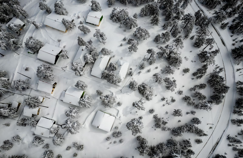 An aerial shot of a suburb of houses in winter covered in snow. 