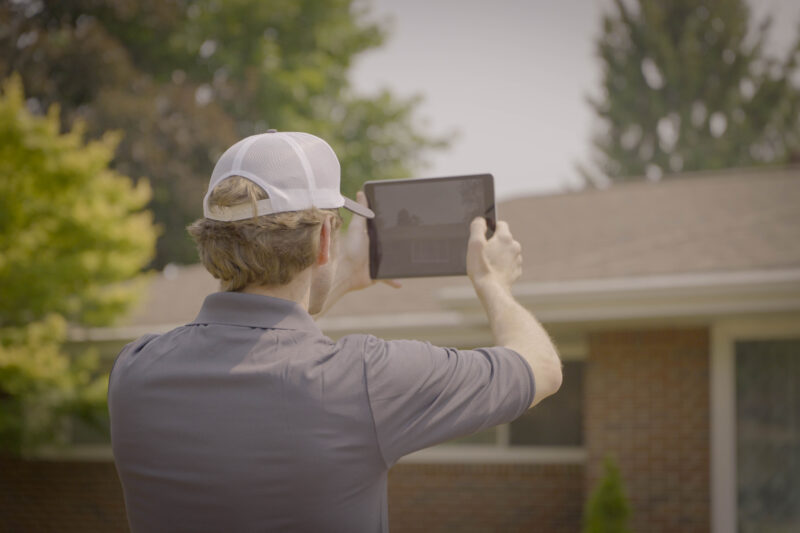 An Erie Home Representative Using State of the Art Technology To Measure A Customers Roof.