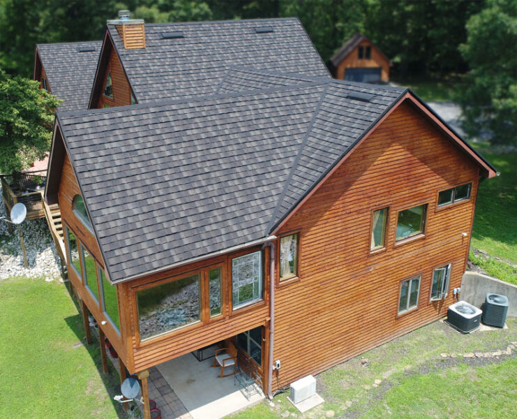 A Beautiful Erie Home Metal Roof featuring a Charcoal, Cottage HD Roof on a cabin in the wood.