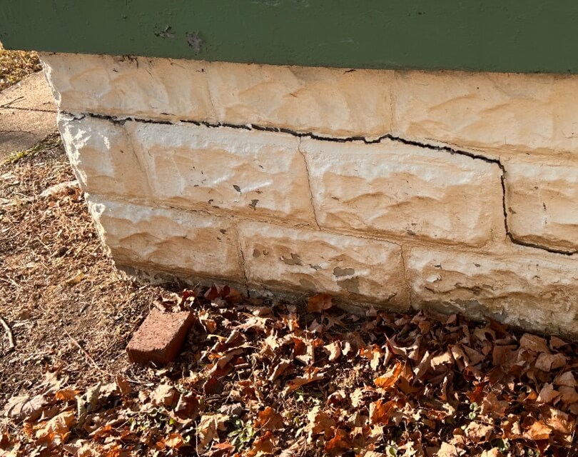 Exposed cracks between large stone bricks on outside foundation wall