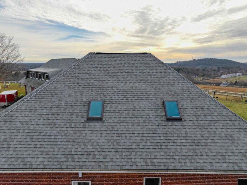 An asphalt roof with skylights. The sun is setting behind the roof.