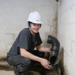 An Erie Home Basement Waterproofing employee installing the drain tile.