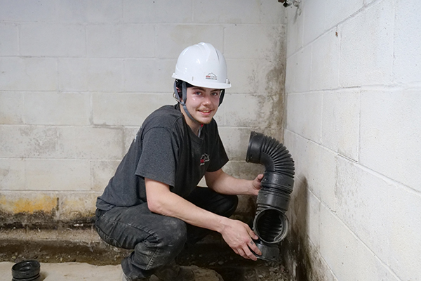 An Erie Home Basement Waterproofing employee installing the drain tile.