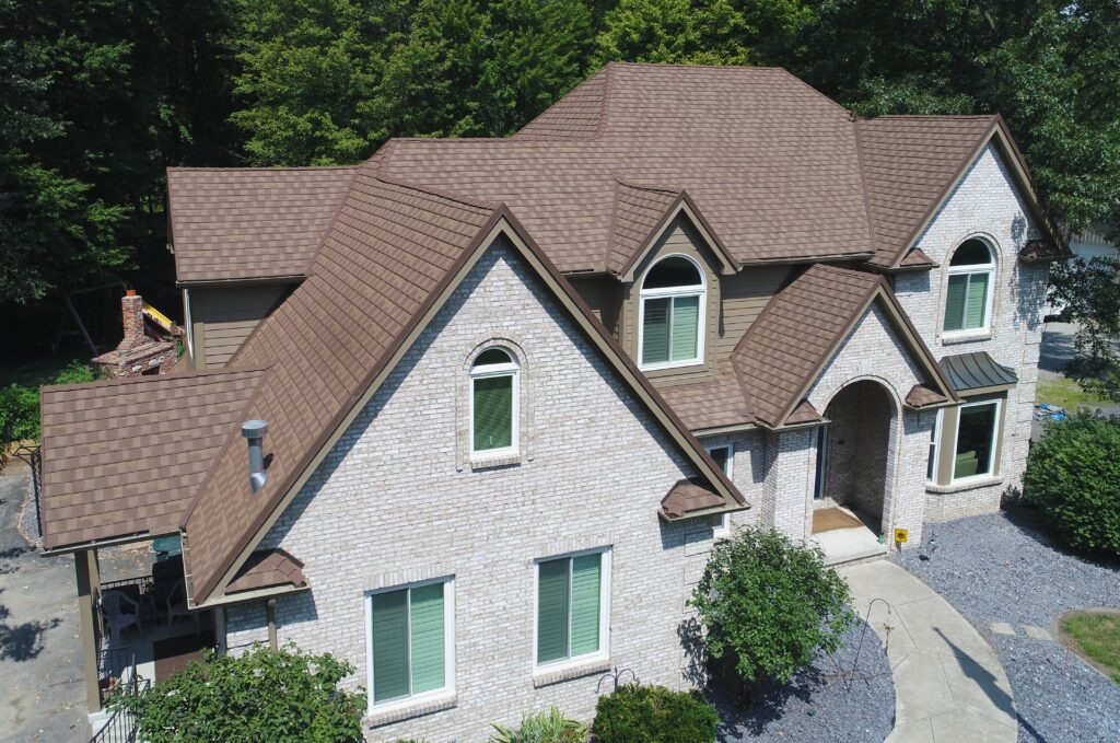 brown metal roof on a gray house in front of trees