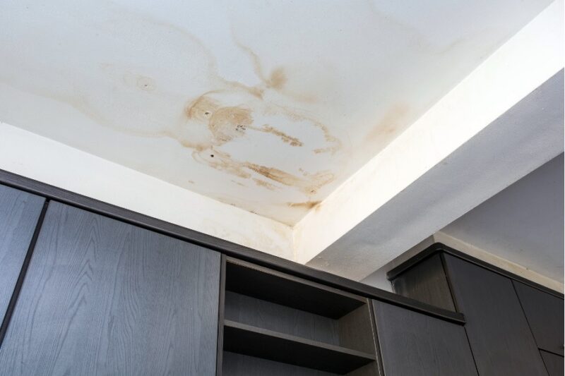 White ceiling with brown water stain from summer roof leak.